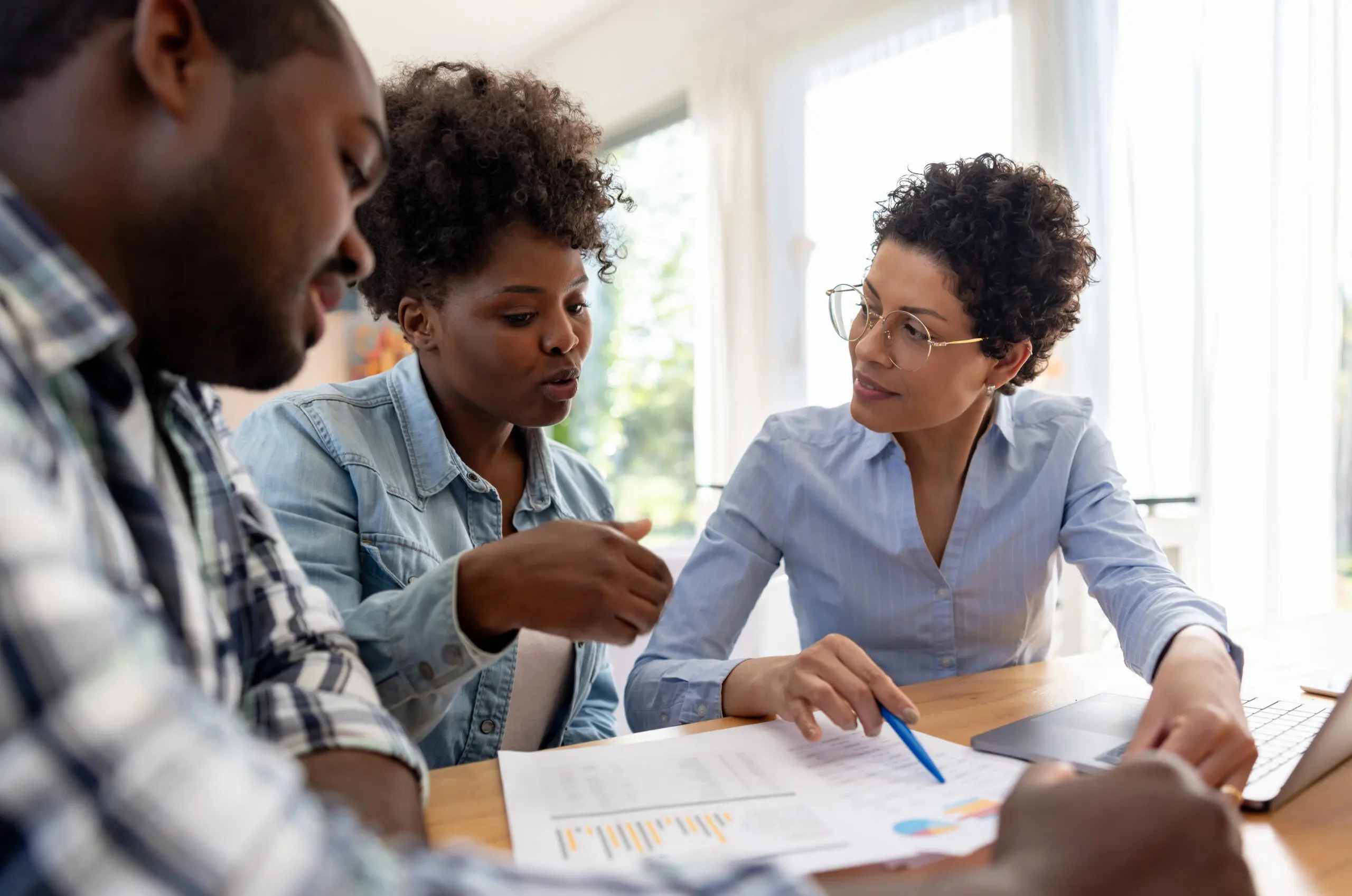 Financial advisor talking to an African American couple at home - home finances concepts